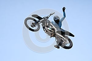 racer in a helmet on a black motorcycle is jumping against the sky