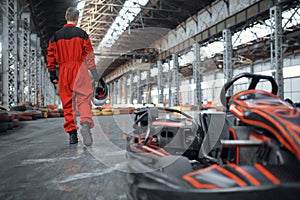 Racer with helmet near go kart car, back view