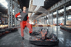 Racer with helmet poses near go kart car, karting