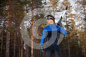 Racer man skier with cross country skis on background of winter forest