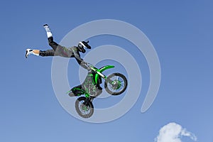 Racer on a motorcycle in flight, jumps and takes off on a springboard against the blue sky