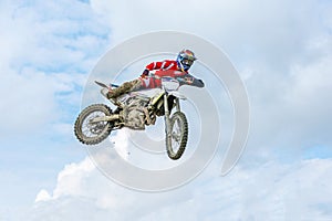 Racer on a motorcycle in flight, jumps and takes off on a springboard against the sky.