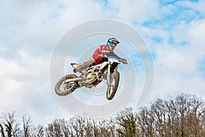 Racer on a motorcycle in flight, jumps and takes off on a springboard against the sky.
