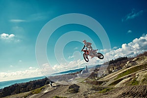 Racer on mountain bike participates in motocross race, takes off and jumps on springboard, against the blue sky. Close