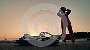 A racer puts on a helmet while standing next to his cart