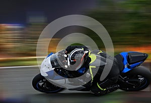 Racing bike rider leaning into a fast corner at high speed with motion blur