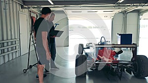 Racing car is getting inspected by two experts