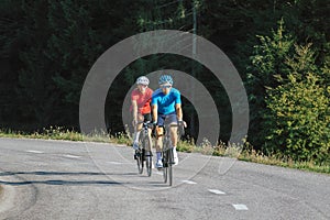 Racing cyclist couple in sports jerseys, pedaling on a road