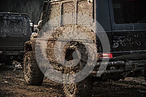 Racing on off-road cars. Dirty offroad cars on dark background, back view.