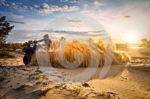 Racing powerful quad bike on the difficult sand in the summer