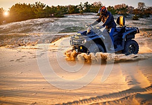 Racing powerful quad bike on the difficult sand in the summer