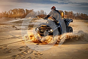 Racing powerful quad bike on the difficult sand in the summer