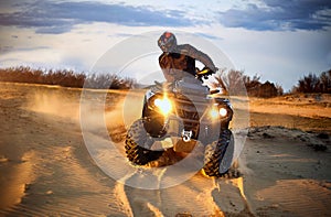 Racing powerful quad bike on the difficult sand in the summer