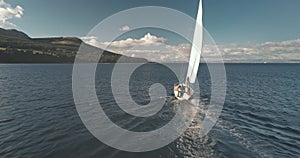 Racing yacht at ocean gulf of Brodick harbor aerial. Mountainous island coast at amazing seascape