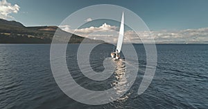 Racing yacht at ocean gulf of Brodick harbor aerial. Mountainous island coast at amazing seascape