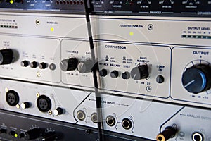 A rack of audio compressors in a recording studio