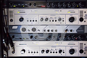 A rack of audio compressors in a recording studio