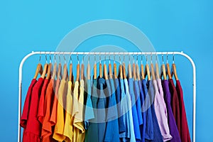 Rack with bright clothes on background. Rainbow colors