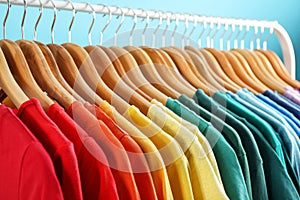Rack with bright clothes on blue. Rainbow colors