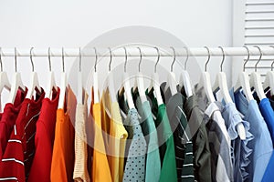 Rack with bright clothes in room