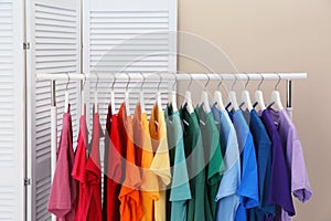 Rack with bright clothes in room
