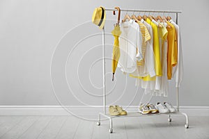 Rack with bright clothes, shoes and accessories near light grey wall indoors, space for text