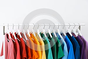 Rack with bright clothes on white background