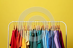 Rack with bright clothes on background. Rainbow colors