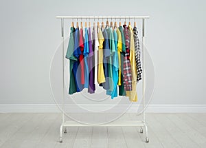 Rack with bright clothes in room