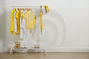 Rack with bright stylish clothes, shoes and accessories near white wall indoors, space for text