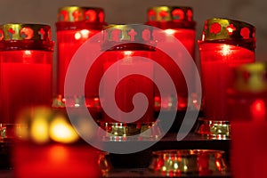 A rack of burning red votive prayer candles in a italian church. Candlelight fire flames in rows are silent religion symbol for