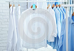 Rack with clean clothes on hangers after dry-cleaning