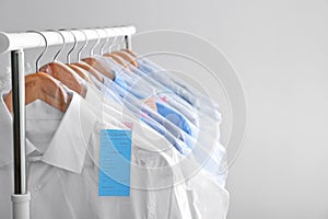 Rack with clean clothes on hangers after dry-cleaning