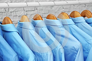 Rack with clean clothes on hangers after dry-cleaning