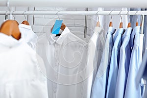 Rack with clean clothes on hangers after dry-cleaning