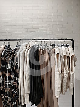 Rack with clothes on hangers in the store against the backdrop of a wall