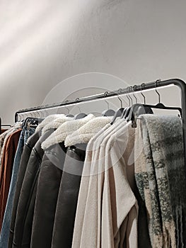 Rack with clothes on hangers in the store against the backdrop of a wall