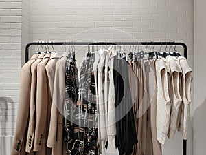 Rack with clothes on hangers in the store against the backdrop of a wall