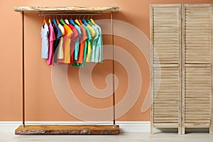 Rack with different child`s clothes near coral wall
