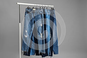 Rack with different jeans on grey