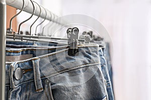 Rack with different jeans indoors, closeup view