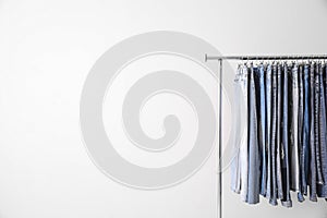 Rack with different jeans on light background. Space for text