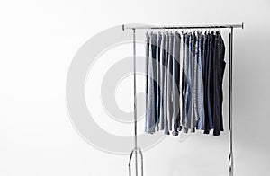 Rack with different jeans near wall. Space for text