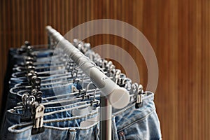 Rack with different jeans on wooden background, closeup