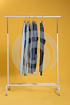 Rack with different jeans on yellow