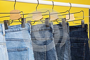 Rack with different jeans on yellow, closeup