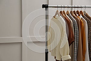 Rack with different stylish clothes near grey wall. Space for text