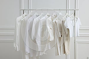 Rack with different stylish women`s clothes near white wall indoors