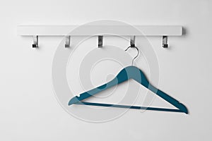 Rack with empty blue clothes hanger on white wall
