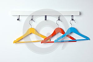Rack with empty bright clothes hangers on white wall